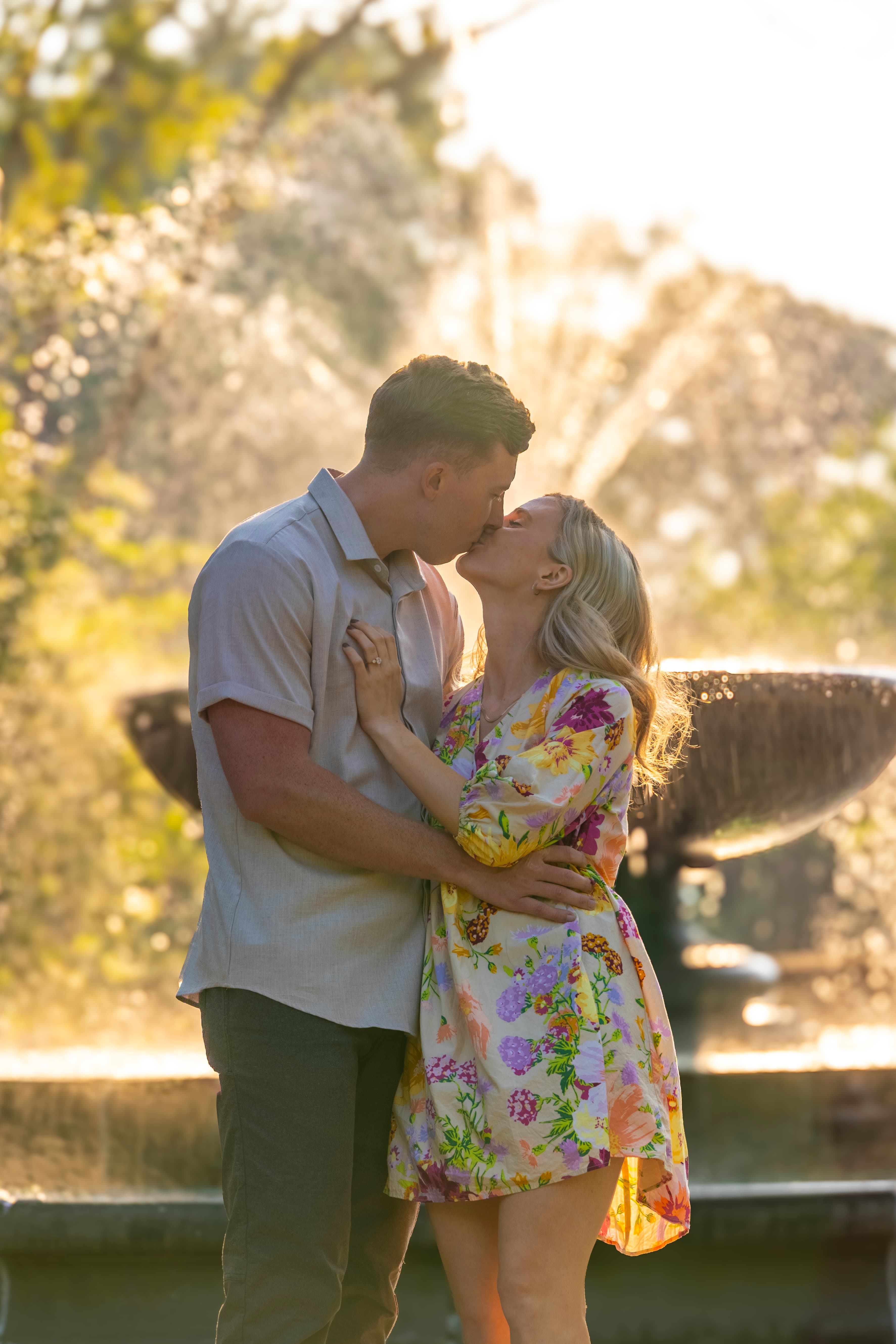 Couple kissing in front of a fountain in golden backlight
