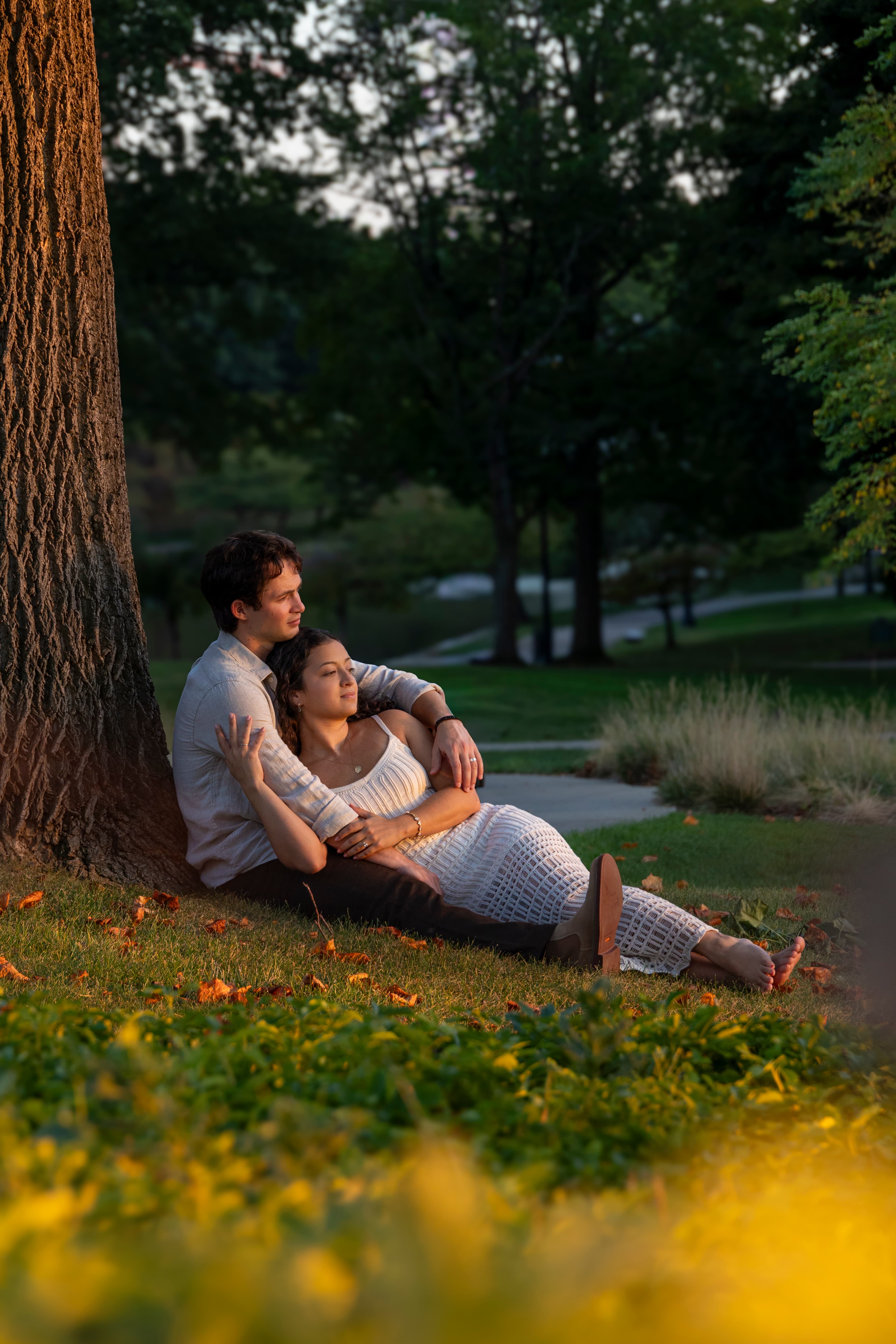 Couple leaning against a tree in autumn park light