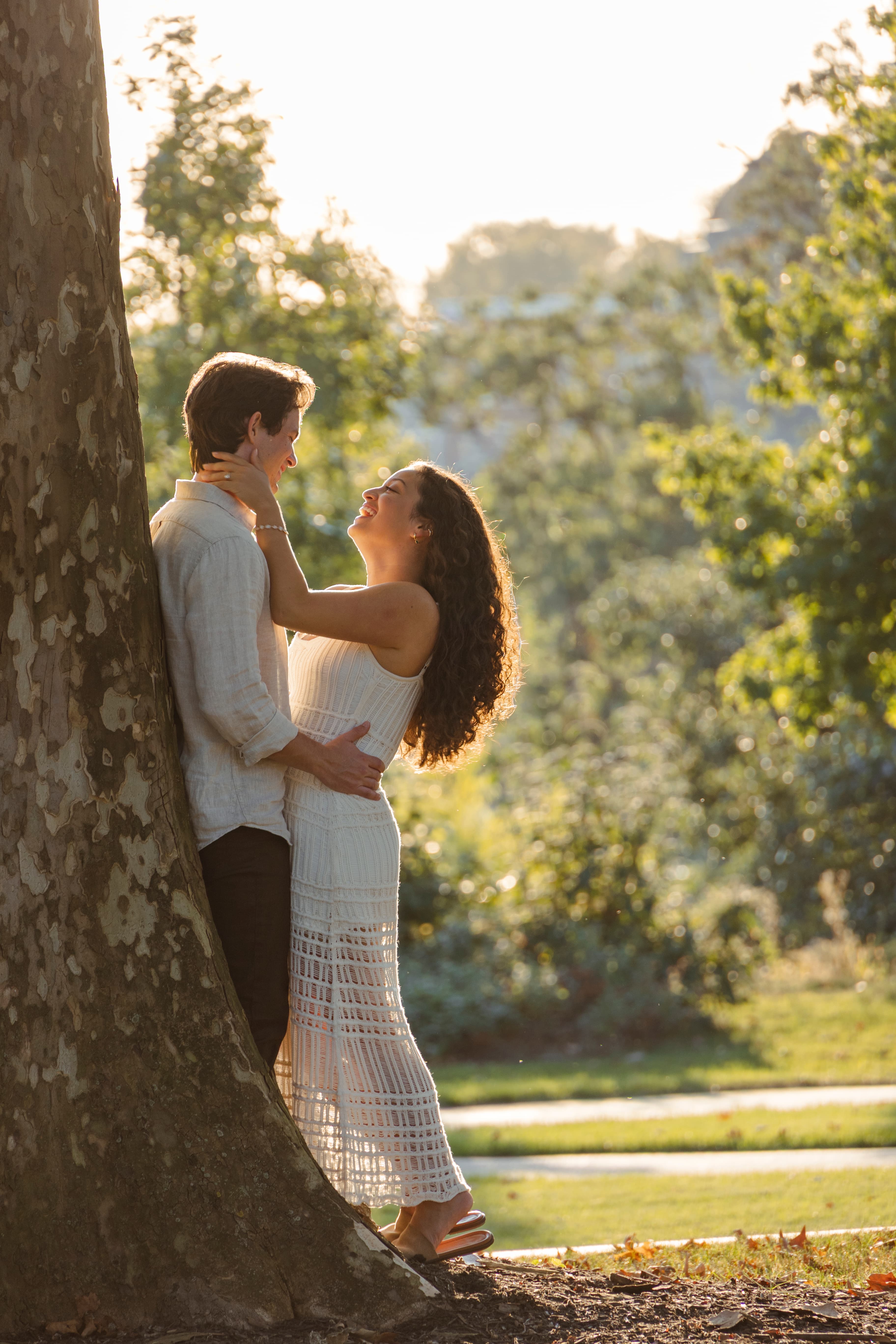 Couple embracing against a large tree in golden light
