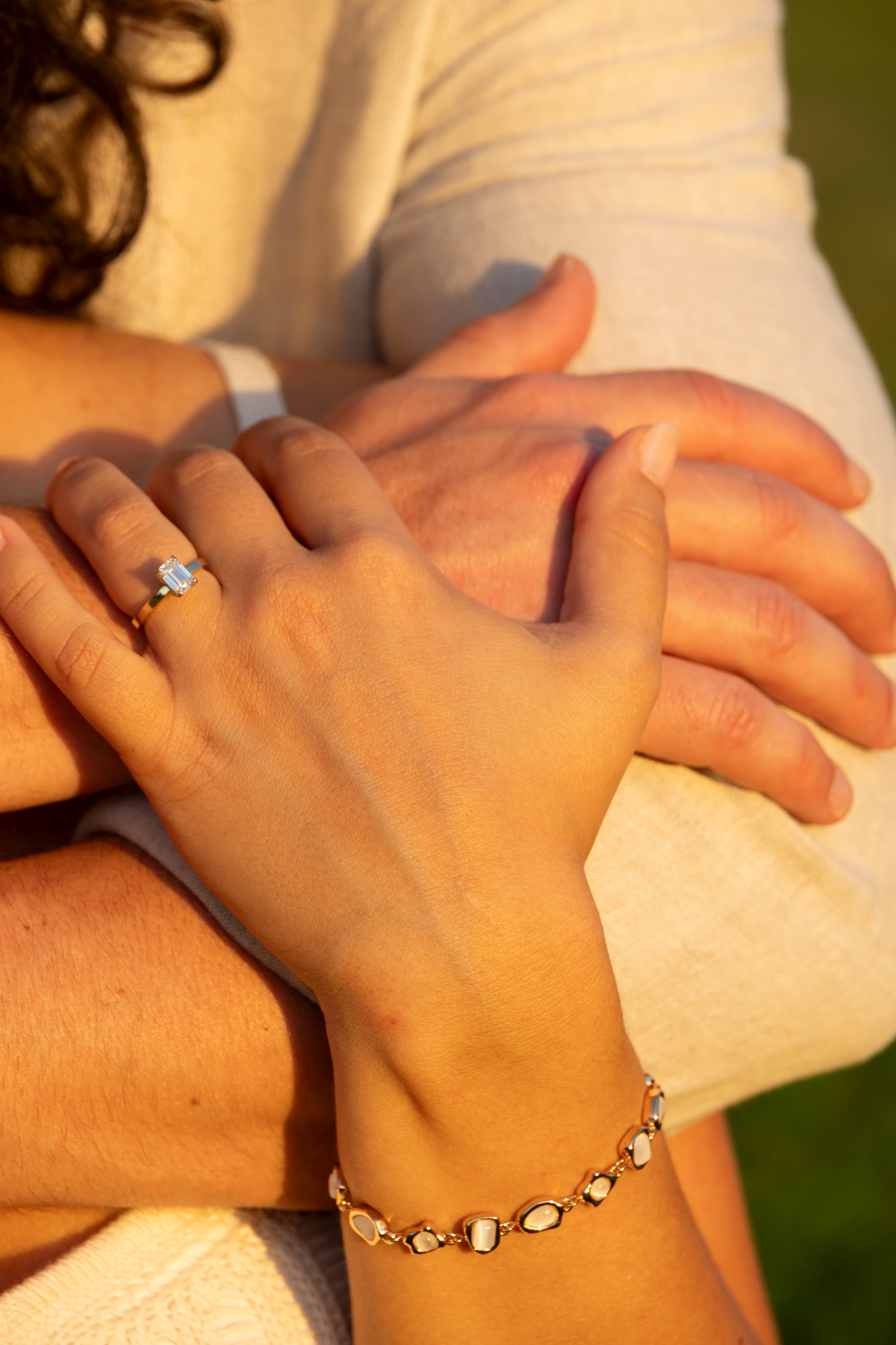 Close-up of engagement ring and intertwined hands