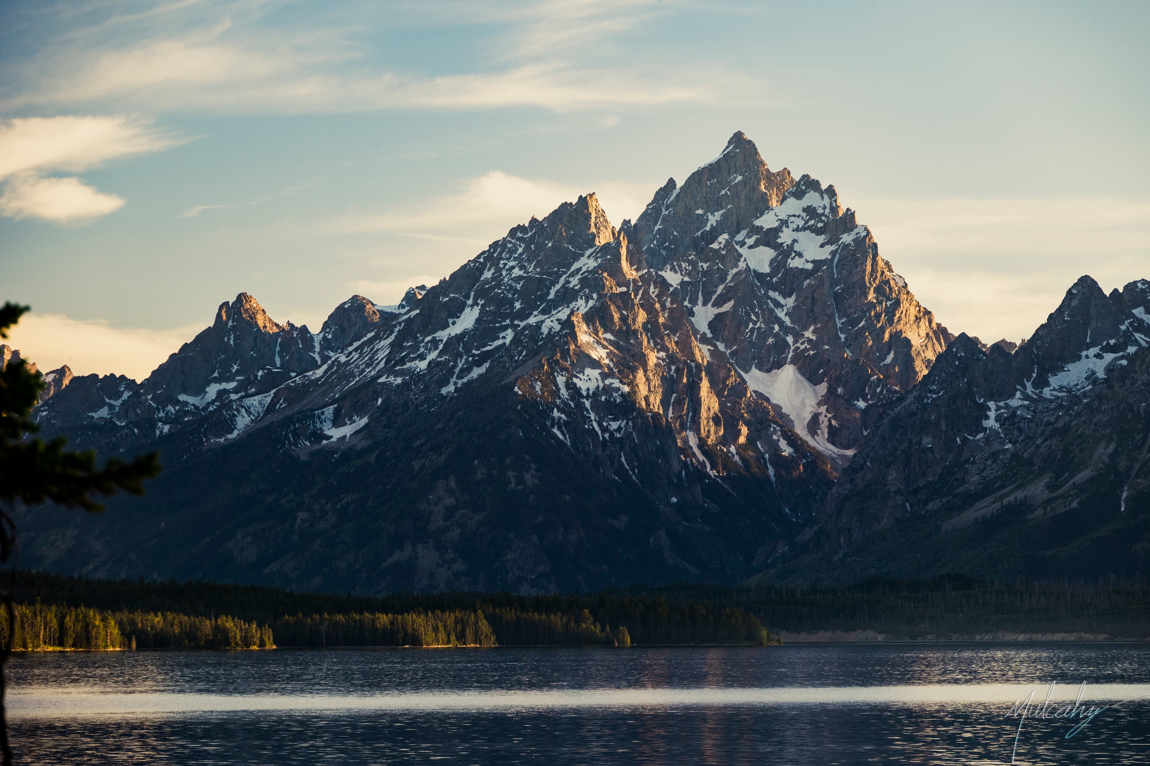 Snow-capped Grand Teton peaks reflected in Jackson Lake at dawn