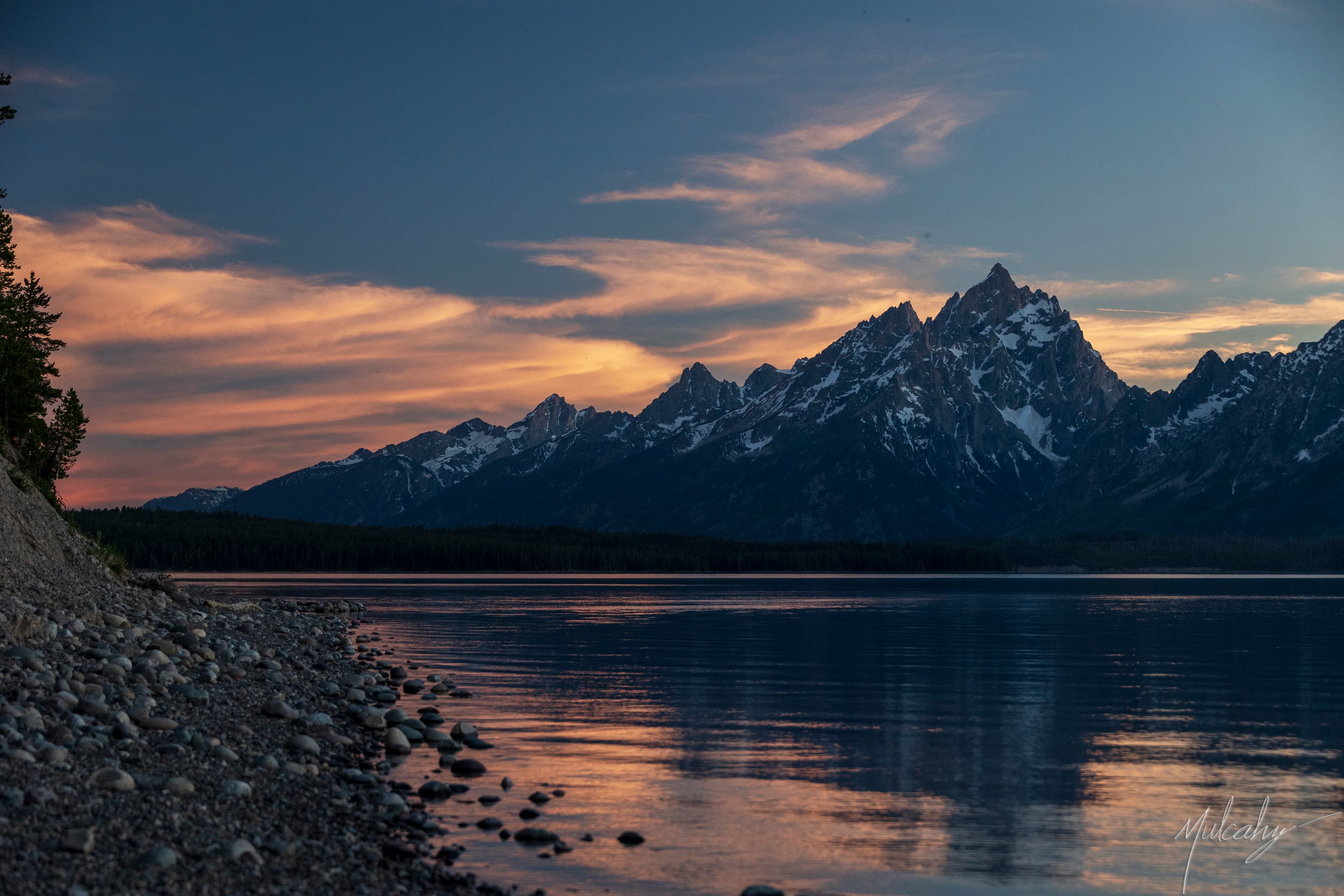 Grand Teton range at sunset, warm sky reflected in Jackson Lake