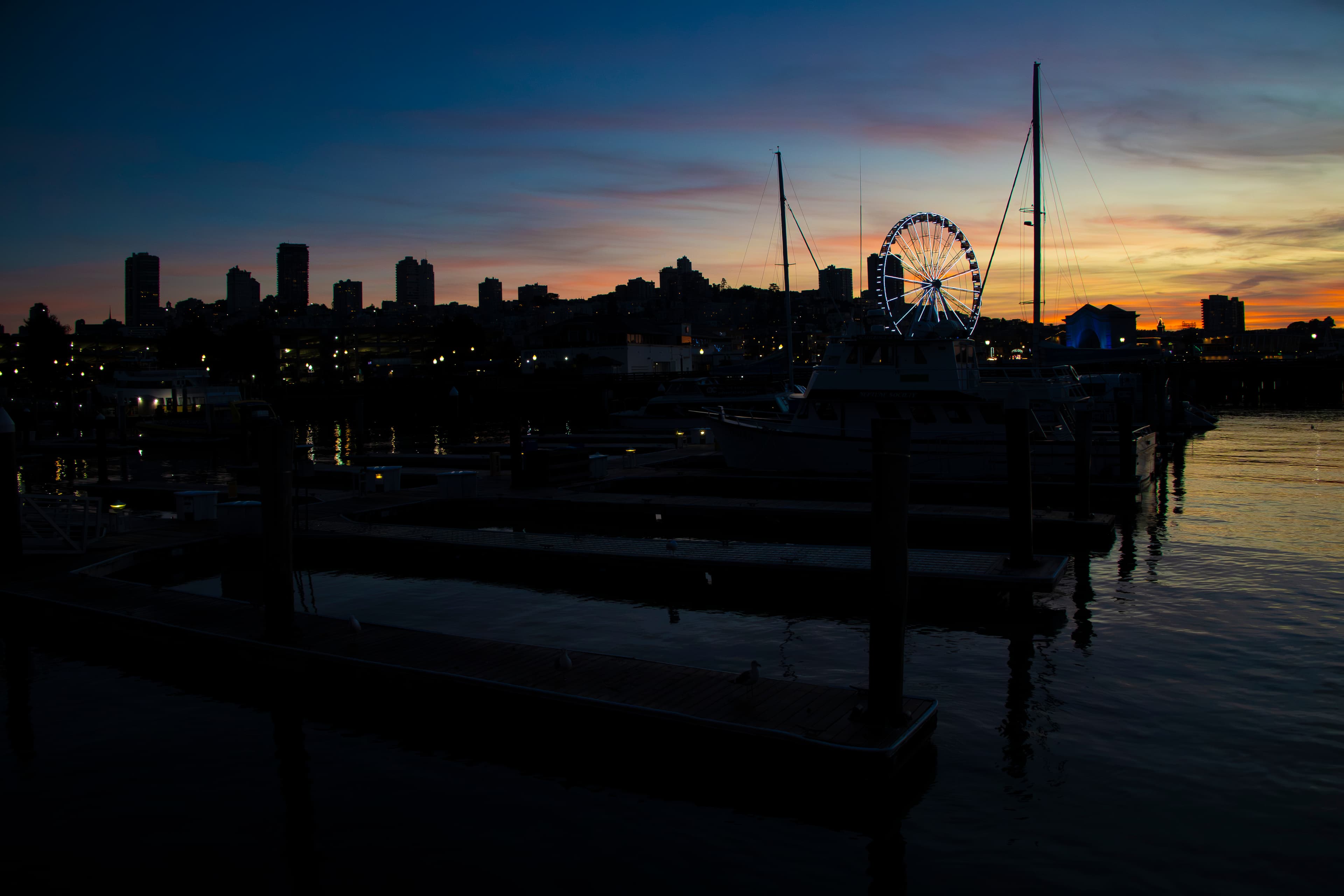 SF city skyline and Ferris wheel silhouetted at twilight from the marina